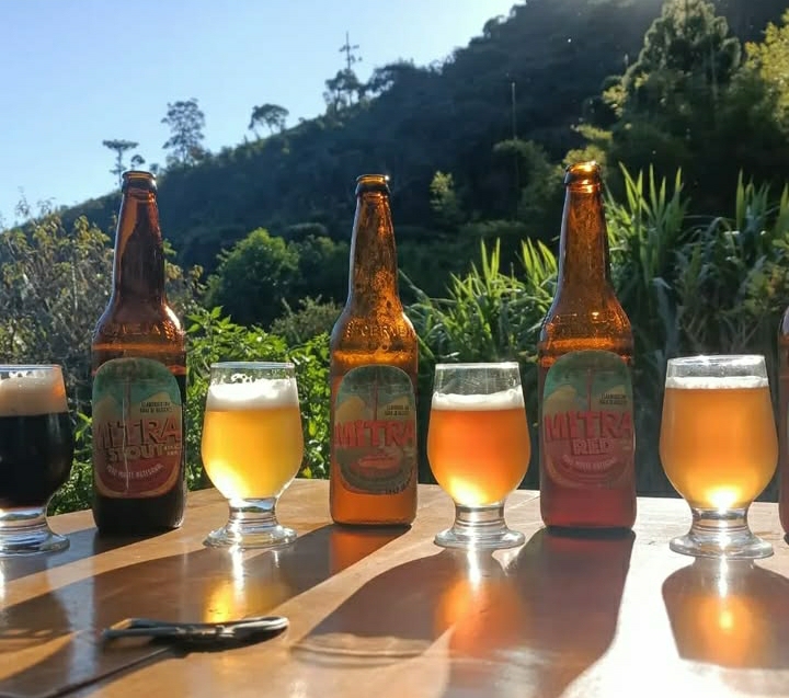 Cervejas Mitra e taças de degustação em uma mesa diante da serra